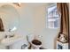 Bright bathroom featuring a modern pedestal sink, toilet, and window providing natural light at 17456 Quarry Way, Monument, CO 80132