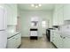 Well-lit kitchen featuring a dishwasher, white cabinets, and unique flooring at 2819 S Bannock St, Englewood, CO 80110