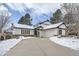 Front view of a remodeled midcentury modern home with a snow covered driveway at 2133 S Parfet Dr, Lakewood, CO 80227