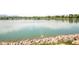 Calm lake view featuring blue water with rocky shoreline and trees in the background at 928 Cimarron Dr # C, Lafayette, CO 80026