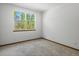 A bright bedroom with natural light, neutral carpeting, and a view of lush greenery outside the window at 7254 S Kellerman Way, Aurora, CO 80016