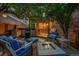 Backyard patio with a fire pit and an outdoor kitchen under string lights and mature trees at 7064 E 2Nd Ave, Denver, CO 80220