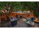 Backyard patio with a fire pit and an outdoor kitchen under string lights and mature trees at 7064 E 2Nd Ave, Denver, CO 80220