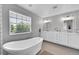 Bright bathroom featuring a soaking tub, a window, and double vanity with white cabinets at 7064 E 2Nd Ave, Denver, CO 80220