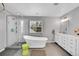 Bright bathroom featuring a soaking tub, glass shower, and double vanity with white cabinets at 7064 E 2Nd Ave, Denver, CO 80220