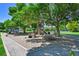 Community playground featuring mature trees, a play structure, and picnic tables at 7064 E 2Nd Ave, Denver, CO 80220