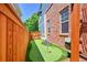 A small putting green is installed next to the house and between a wood fence and brick wall at 7064 E 2Nd Ave, Denver, CO 80220