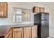 Galley kitchen with oak cabinets, black appliances, laminate countertops and open pass-through to living area at 821 Stony Mesa Pl, Castle Rock, CO 80108