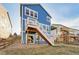 Bright blue two-story home featuring dual wooden staircases leading to upper decks and a walkout basement at 786 Sundance Ln, Erie, CO 80516