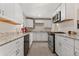 Well-lit kitchen featuring stainless steel appliances, tile floor and white cabinets at 1599 W Beekman Pl, Denver, CO 80221