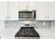 Stainless steel microwave and stovetop with gray backsplash and white cabinets at 1957 S Coolidge Way, Aurora, CO 80018