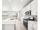 Open kitchen featuring a large island, stainless appliances, tile backsplash, and light hardwood floors at 1957 S Coolidge Way, Aurora, CO 80018