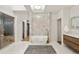 Bright bathroom featuring a soaking tub, marble tile accent wall, glass enclosed shower and wood vanity at 93 Glenmoor Dr, Cherry Hills Village, CO 80113