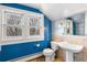 Bright blue bathroom with a pedestal sink, tiled accents, and natural light from the bright double windows at 1827 N Bellaire St, Denver, CO 80220