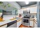 Galley kitchen featuring stainless steel appliances, white cabinets, and stylish hanging plants at 5745 W Atlantic Pl # 104, Lakewood, CO 80227
