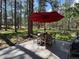 Cozy backyard patio featuring a round wooden table set and a large red umbrella for shade at 85 S Sherwood Gln, Monument, CO 80132