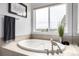 A luxurious soaking tub positioned beneath a large window offering serene views at 8802 E 148Th Ln, Thornton, CO 80602