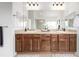 Elegant bathroom featuring double sinks, mirrors, warm lighting, and neutral color palette at 8802 E 148Th Ln, Thornton, CO 80602