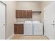 Functional laundry room features tile flooring, wooden cabinetry, sink and modern washer and dryer at 8802 E 148Th Ln, Thornton, CO 80602