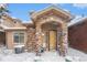 Townhome's front entrance with stone archway, snowy landscaping at 8551 Gold Peak Dr # B, Highlands Ranch, CO 80130