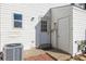White exterior with A/C unit, utility access, a small patio, and backyard lawn space at 3281 S Estes St, Lakewood, CO 80227