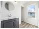 Bathroom with a modern vanity, round mirror, and a window bringing in natural light at 3281 S Estes St, Lakewood, CO 80227