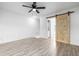 Bedroom featuring a ceiling fan, wood-look floors, and a stylish sliding barn door at 3281 S Estes St, Lakewood, CO 80227