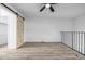 Loft with wood-look floors, a sliding barn door, and black metal railing at 3281 S Estes St, Lakewood, CO 80227