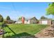 Backyard view of the home featuring lush lawn, a shed, and mature trees under a blue sky at 7600 Kline Dr, Arvada, CO 80005
