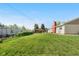 Expansive backyard featuring lush green grass, garden area, and a charming cabin-like structure at 7600 Kline Dr, Arvada, CO 80005