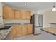 View of the kitchen featuring a stainless steel refrigerator and natural wood cabinets at 15650 E Eldorado Dr, Aurora, CO 80013