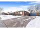 Front view of a brick home with a driveway, snowy lawn, and a detached garage at 1381 Mariposa Dr, Denver, CO 80221