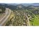 Panoramic aerial view of a forested neighborhood near a highway with rolling mountains at 30206 Telluride Ln, Evergreen, CO 80439