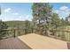 Wide angle view of the wood deck with metal railings and treed landscape beyond at 30206 Telluride Ln, Evergreen, CO 80439