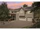 Exterior shot of the home with a large driveway, three car garage, and solar panels at sunset at 30206 Telluride Ln, Evergreen, CO 80439