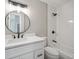 Modern bathroom featuring a round mirror, white vanity, and a sleek shower-tub combination with black fixtures at 10506 Brown Fox Trl, Littleton, CO 80125