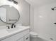 Modern bathroom with a large round mirror, white vanity with black hardware, and a walk-in shower at 10506 Brown Fox Trl, Littleton, CO 80125