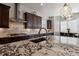 Close-up of kitchen island with granite countertop, stainless steel range hood, and dark wood cabinetry at 12938 Bridge View Ln, Parker, CO 80134