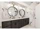 A primary bathroom featuring double sinks, marble walls, decorative lighting and round mirrors at 12457 Topaz Vista Way, Castle Pines, CO 80108
