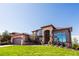 Stunning two-story home featuring stone accents, a well-manicured lawn, and a grand arched entryway at 12457 Topaz Vista Way, Castle Pines, CO 80108
