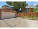View of the garage, driveway, wooden fence, and the brick back of the house with a small yard at 1160 York St, Denver, CO 80206