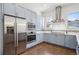 Well-equipped kitchen with stainless appliances, blue cabinets, tile backsplash, and wood floors at 4958 Valentia Ct, Denver, CO 80238