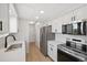 Modern kitchen featuring stainless steel appliances, white cabinets, and quartz countertops at 14552 E Tufts Ave, Aurora, CO 80015