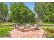 Landscaped backyard with a stone fire pit, seating, and mature trees at 7355 Nile St, Arvada, CO 80007