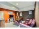 Basement den area featuring a leather sofa, brown accent wall, and an entertainment center at 7355 Nile St, Arvada, CO 80007