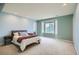 Serene bedroom features a large window, neutral carpet, and soothing blue walls at 7355 Nile St, Arvada, CO 80007