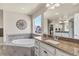 Elegant main bathroom with a soaking tub, granite countertop, vanity, and a bright window with neighborhood views at 3421 E 143Rd Dr, Thornton, CO 80602