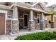 Inviting porch with stone pillars, dark front door, and a seating area for relaxing outdoors at 3421 E 143Rd Dr, Thornton, CO 80602