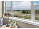 Bright window with a scenic view overlooking a lake and lush greenery, complemented by a Tiffany lamp and colorful plant at 3421 E 143Rd Dr, Thornton, CO 80602