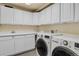 The laundry room has white cabinets, sink and white front load washer and dryer at 693 Syracuse St, Denver, CO 80230